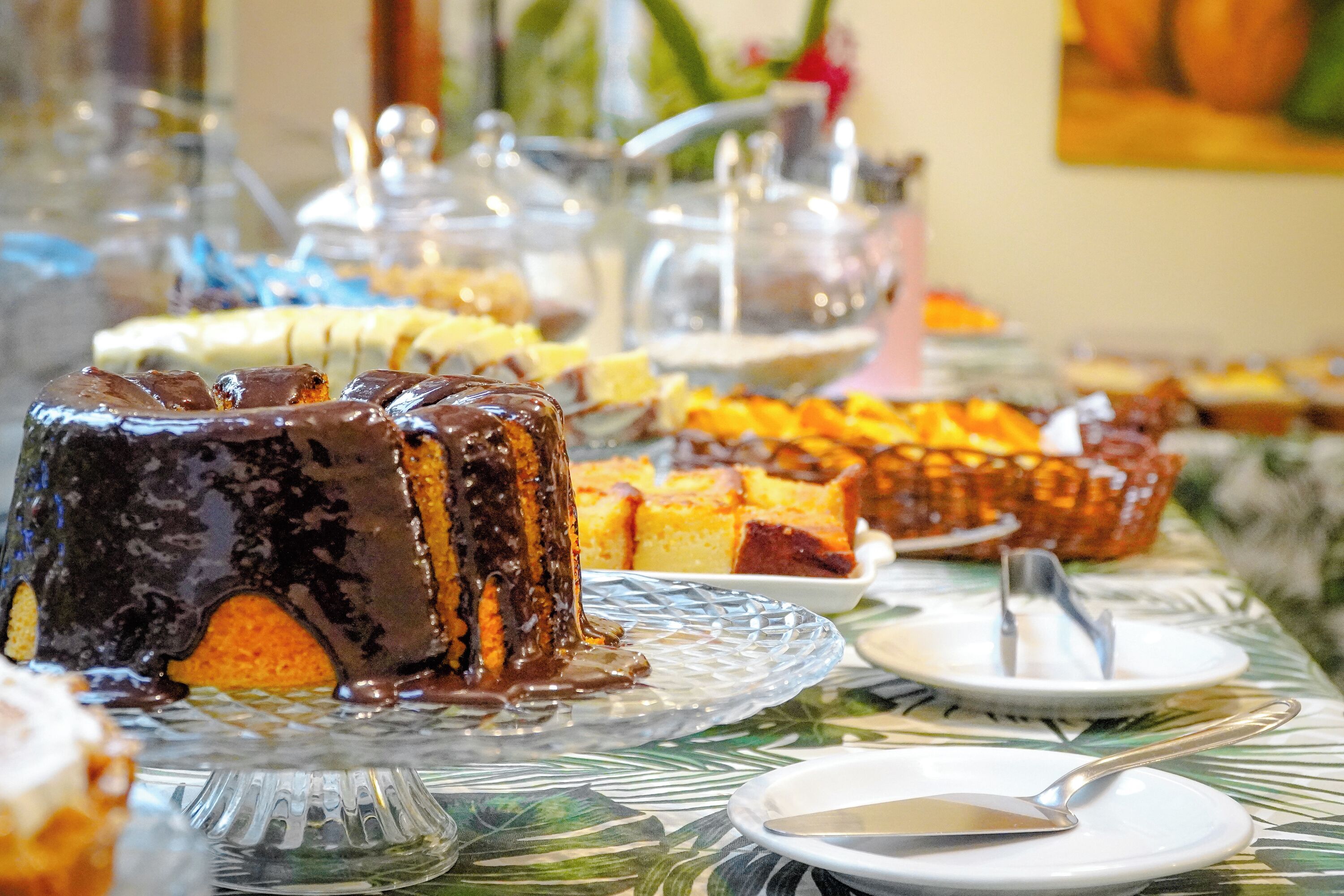 A buffet table with various desserts and a cake on a glass stand.