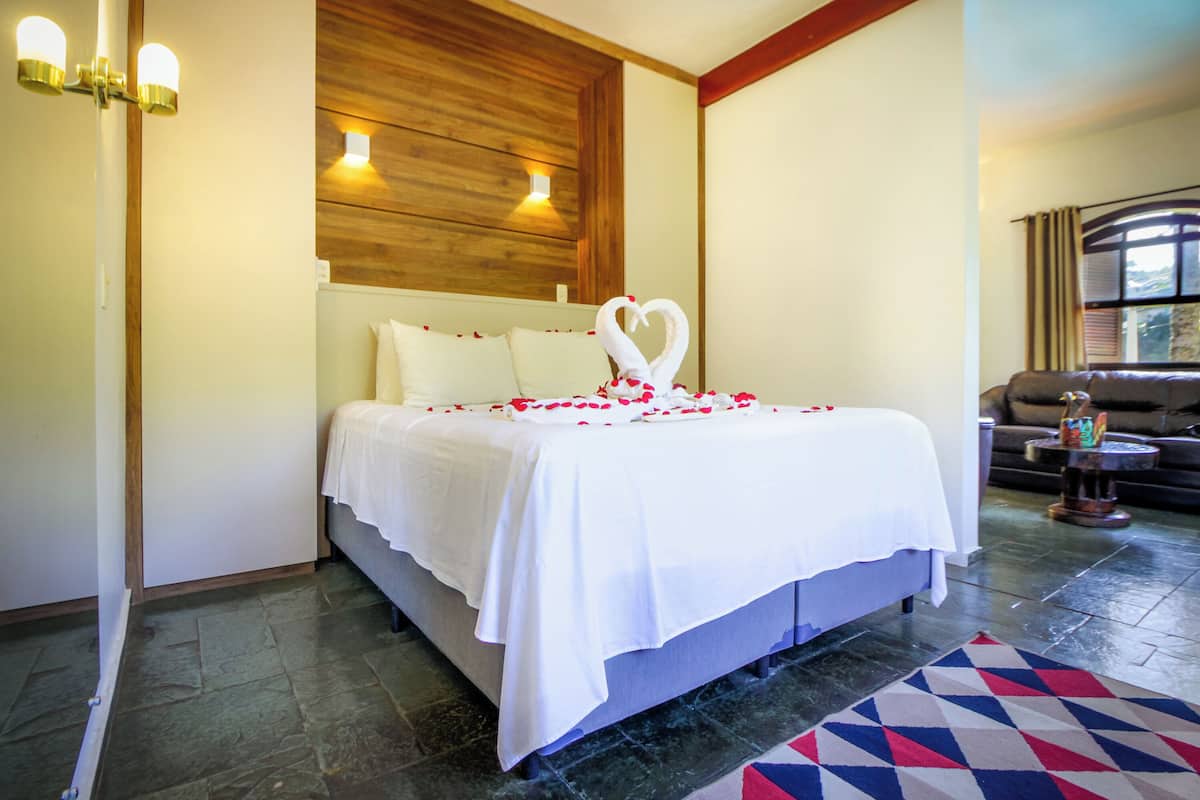 Une chambre d’hôtel avec un lit, une tête de lit en bois, une lampe fixée au mur et un tapis à motifs.