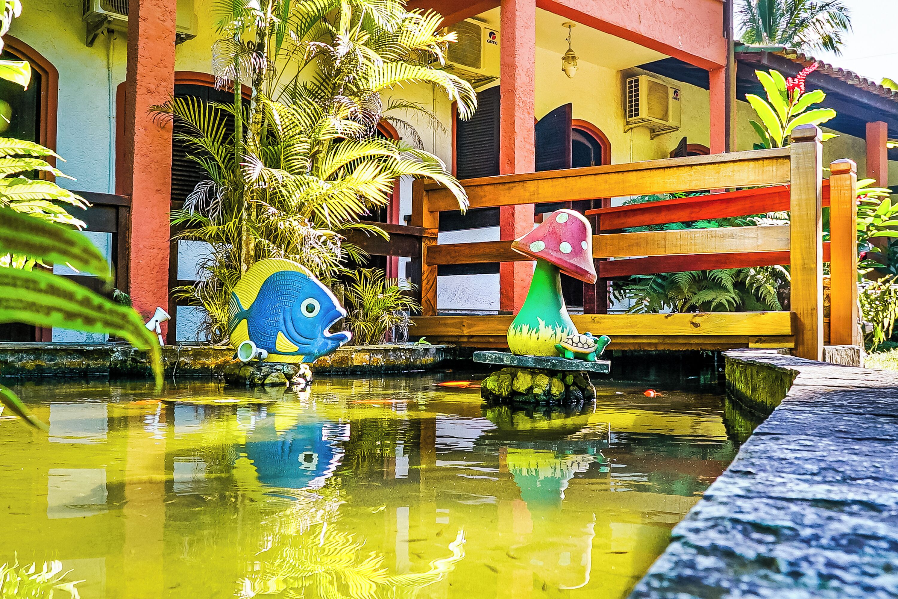 Une fontaine colorée ornée de sculptures de poissons et un banc en bois dans une cour.