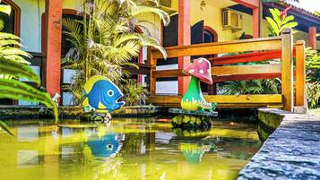Une fontaine colorée ornée de sculptures de poissons et un banc en bois dans une cour.