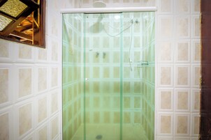 Un box de ducha con paredes de vidrio, revestimiento de azulejos y marco de puerta de madera.