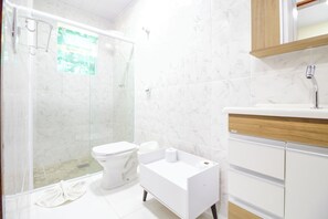 Enjoy a refreshing shower in this bathroom, featuring a glass-enclosed shower area and a convenient toilet, sink, and storage space.