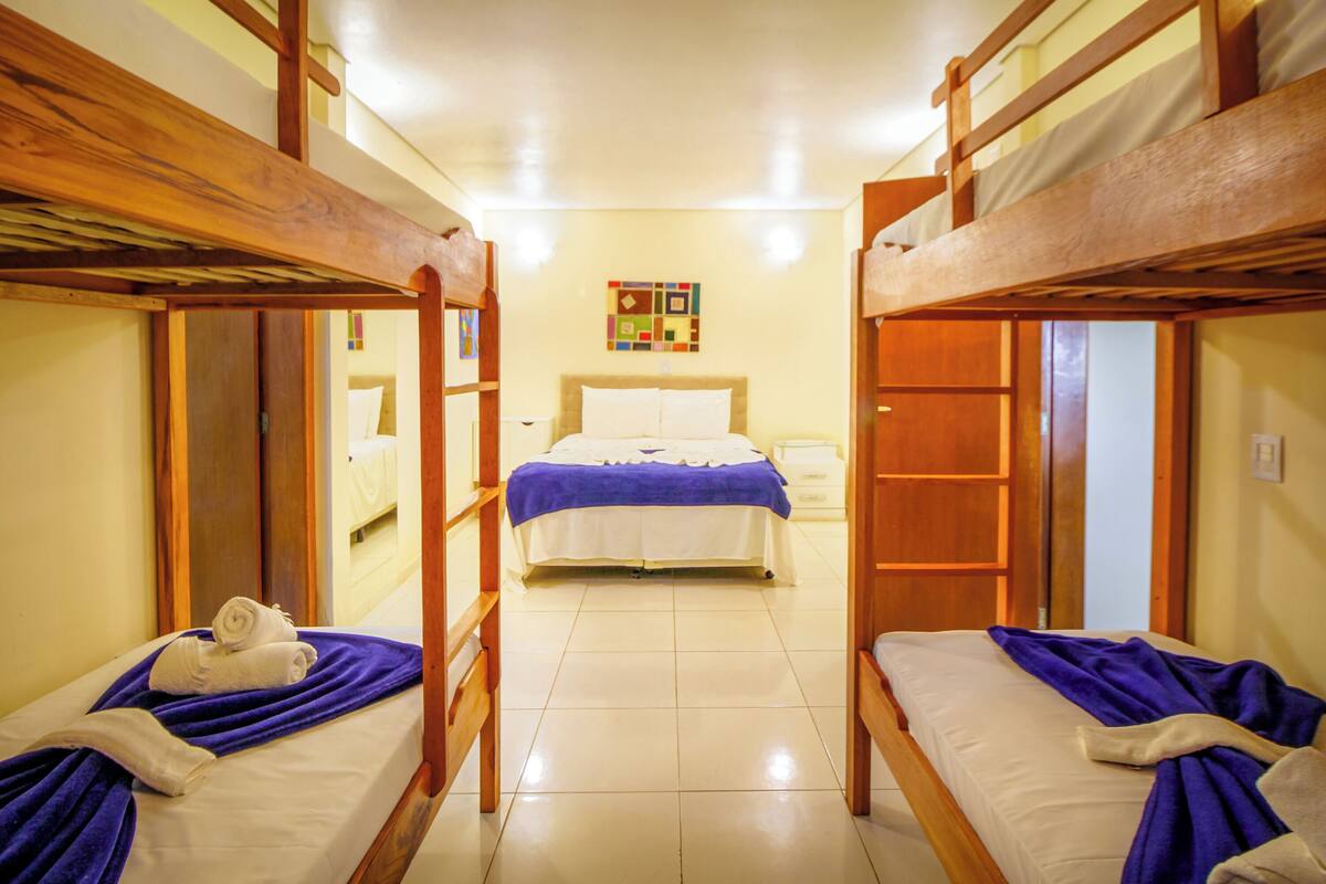 Une chambre avec des lits superposés, un lit principal et une petite salle de bain.