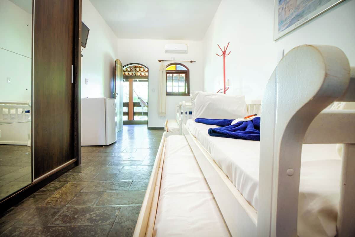 Une chambre d’hôtel avec un lit, un bureau, une chaise, une télévision et une fenêtre.