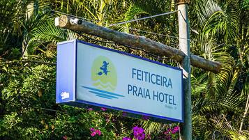 A sign for the Feiticeira Praia Hotel with a logo of a person on a surfboard.