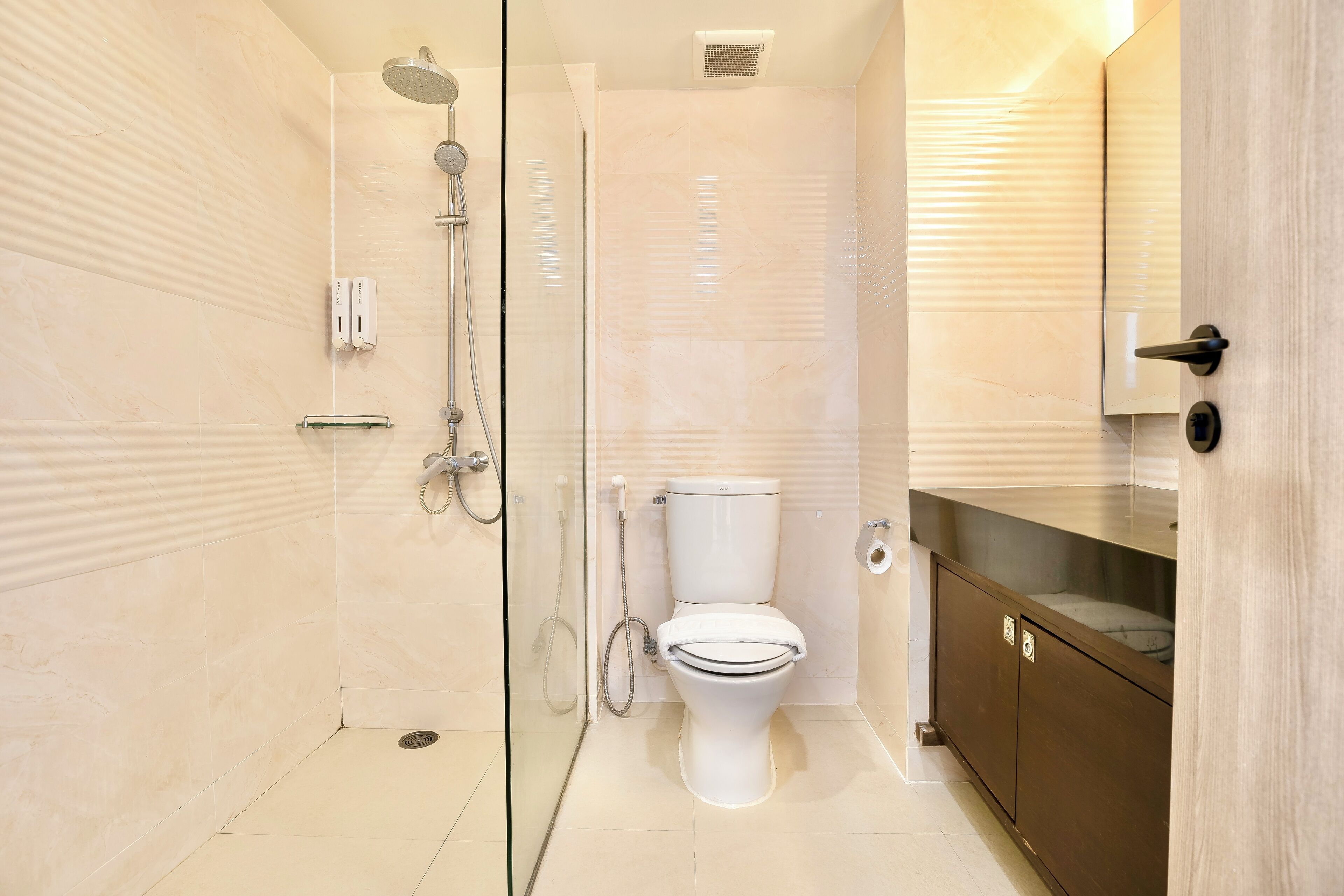 Un baño moderno con cabina de ducha de vidrio, inodoro blanco y tocador de madera con espejo.