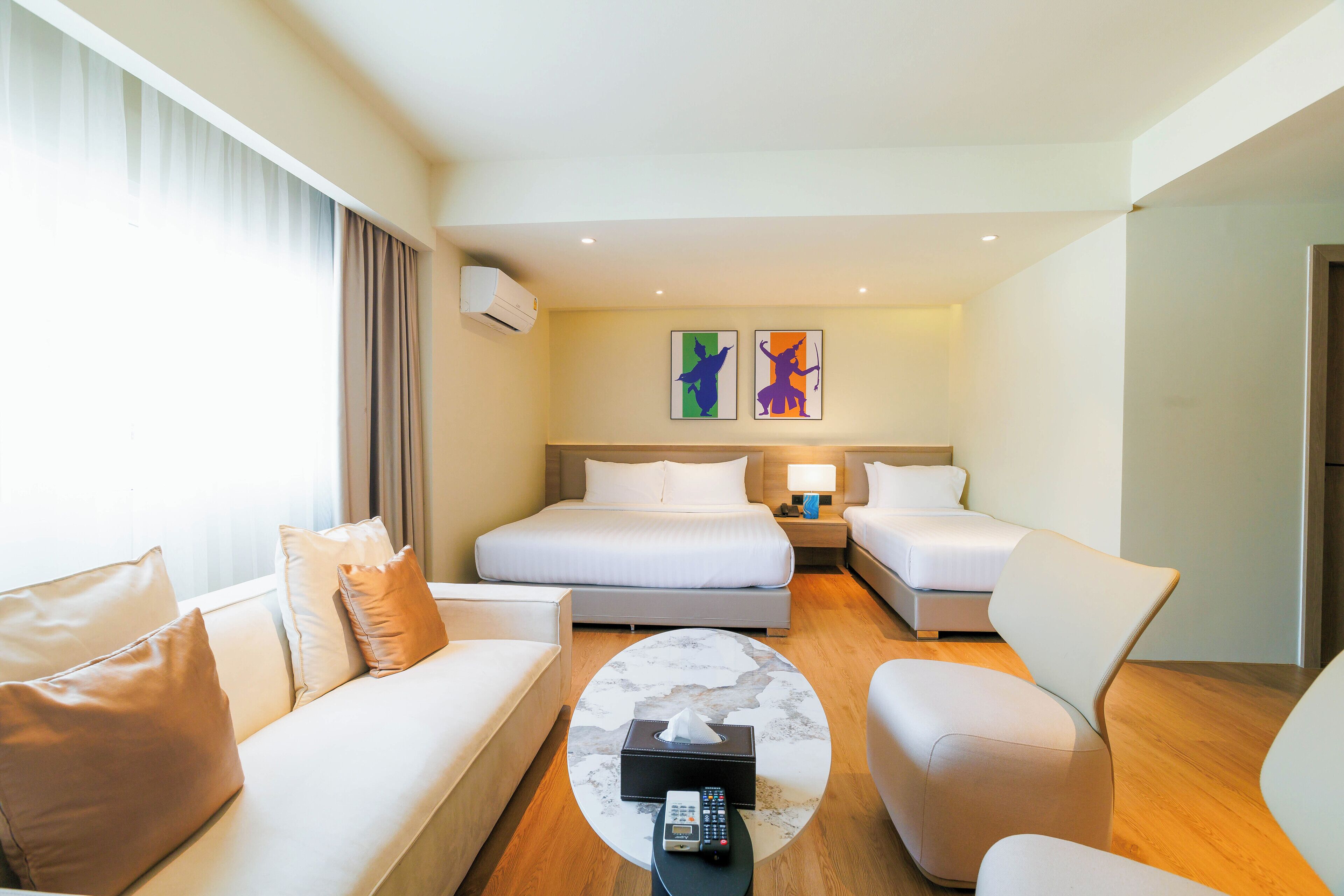 A hotel room with a bed, two bedside tables, a sofa, a coffee table, and a TV.