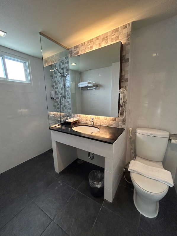 Une salle de bain moderne avec un grand miroir, un lavabo, des toilettes et une douche.