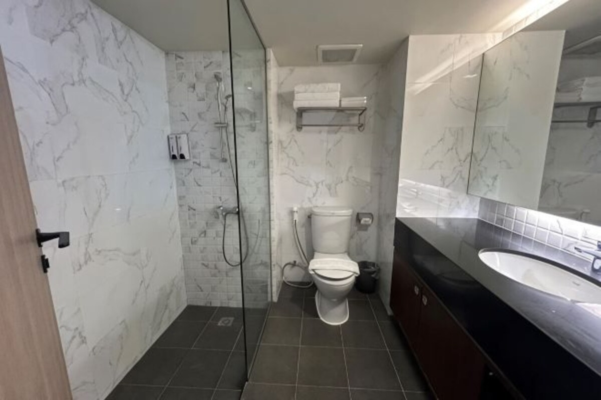 A bathroom with a glass-enclosed shower, a toilet, a sink, and a mirror.