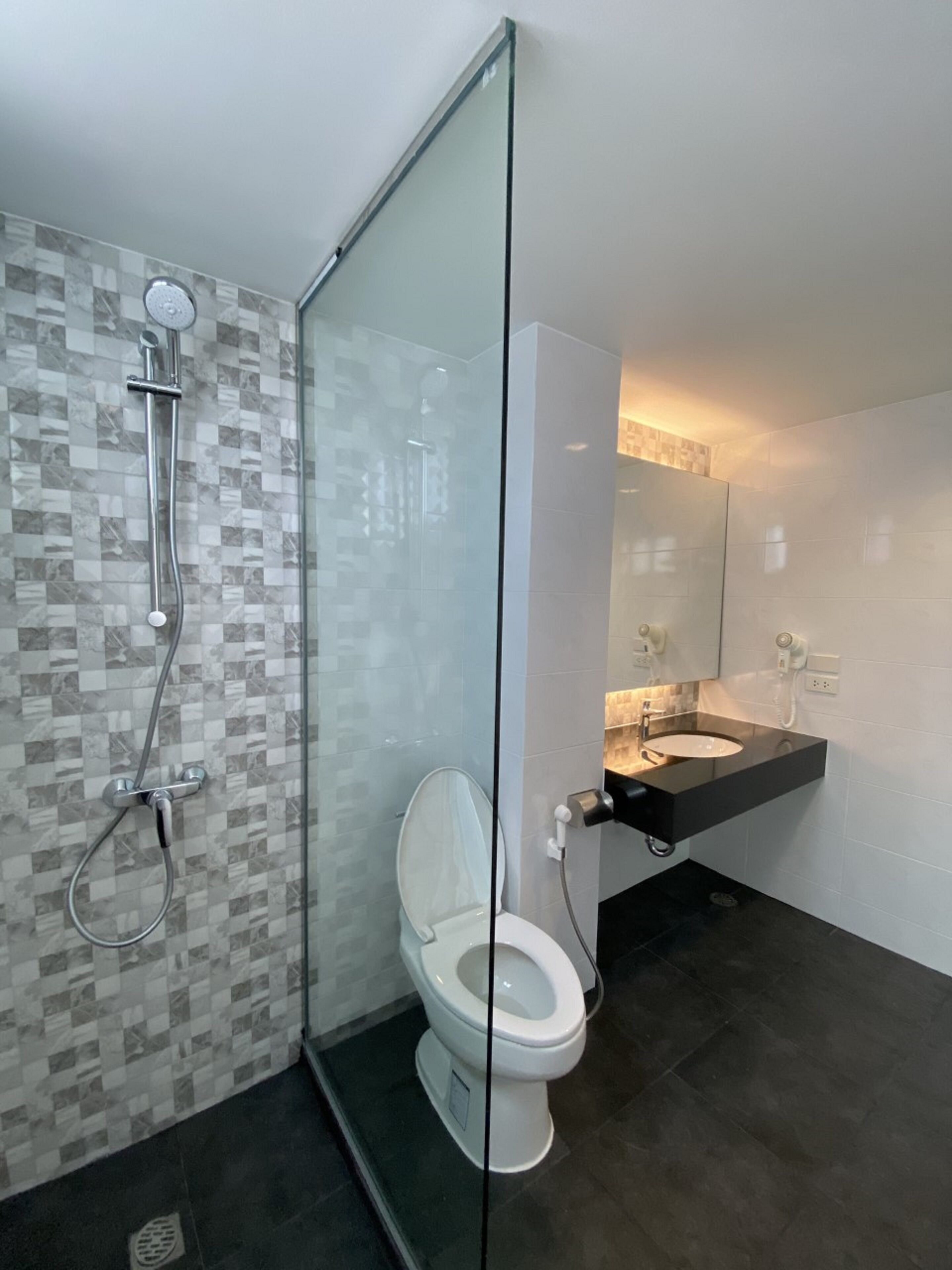 A modern bathroom with a glass shower enclosure, a white toilet, and a black vanity with a mirror.