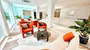 A modern hotel lobby with a white sofa, orange armchairs, and a glass coffee table. - The One Hotel Bay Breeze Pattaya (Pattaya)