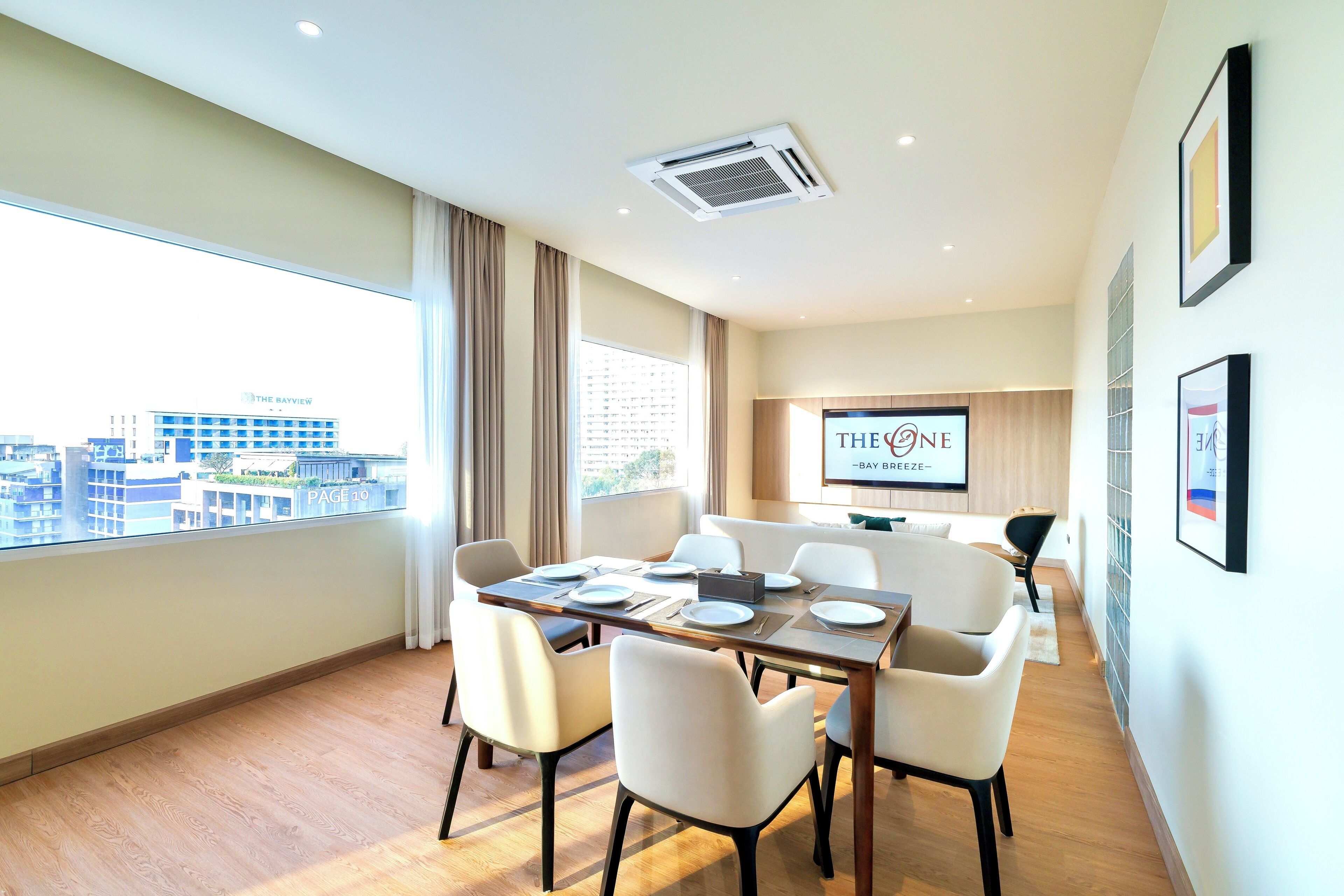 Ein modernes Hotelzimmer mit Essbereich, großen Fenstern und Blick auf die Stadt.