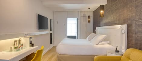 Una habitación de hotel moderna con una cama, un escritorio, una silla amarilla y un sofá.