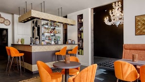 Een moderne bar met een toog, meerdere stoelen en een kroonluchter.