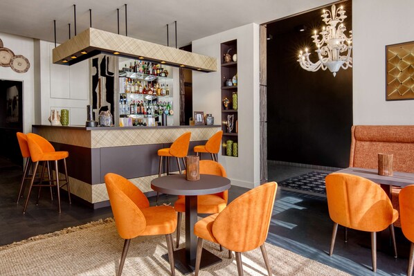 Un espace bar moderne comprenant un comptoir, plusieurs chaises et un lustre.