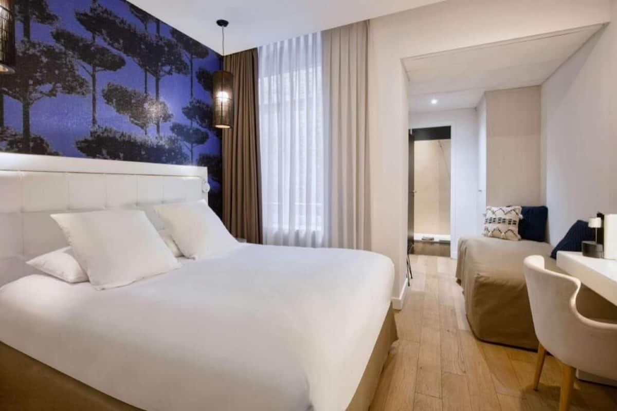 Une chambre d’hôtel avec un grand lit, un bureau et une vue sur une forêt par la fenêtre.