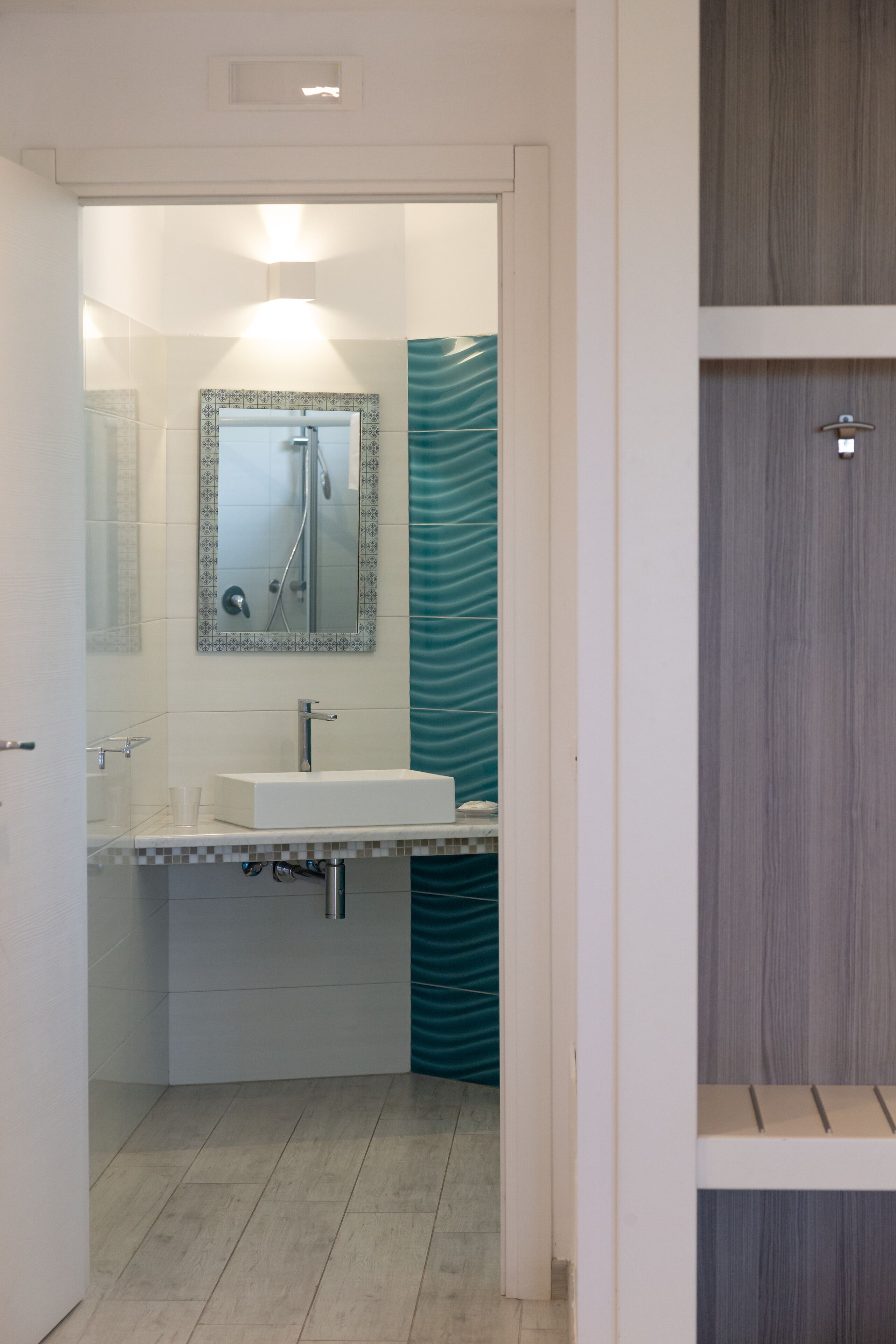 Un baño moderno con un lavamanos blanco, un espejo con marco decorativo y una zona de ducha.