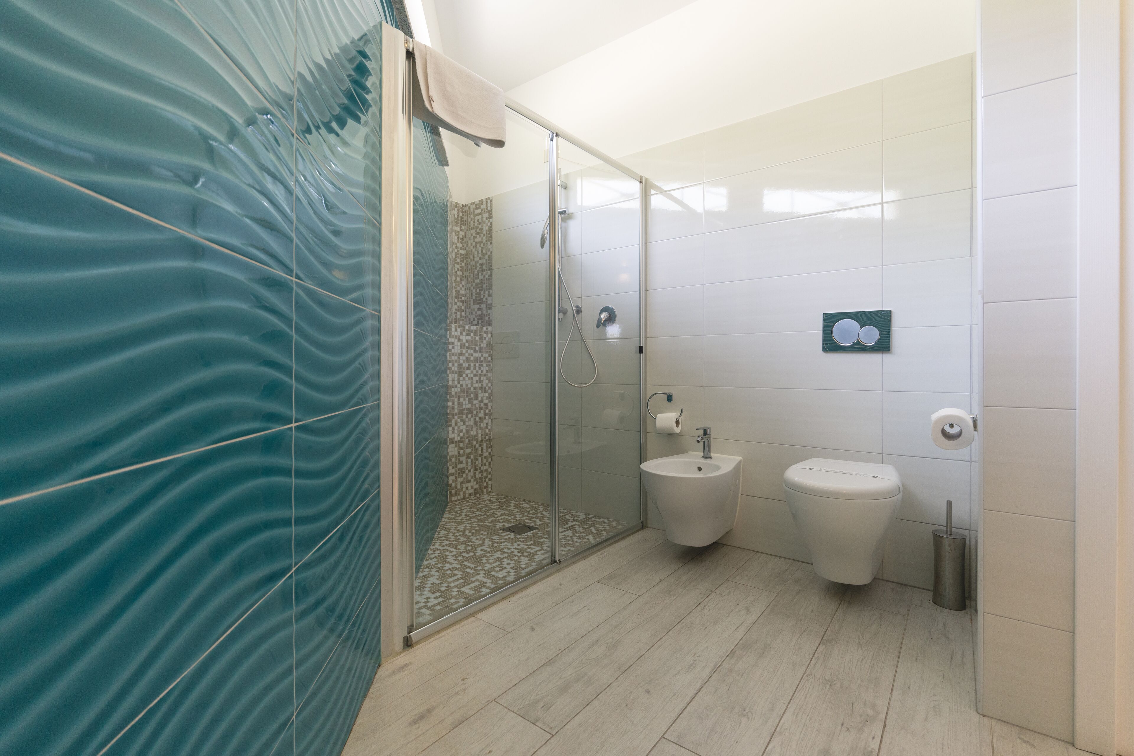 A modern bathroom with a glass shower enclosure, a bidet, and a toilet.
