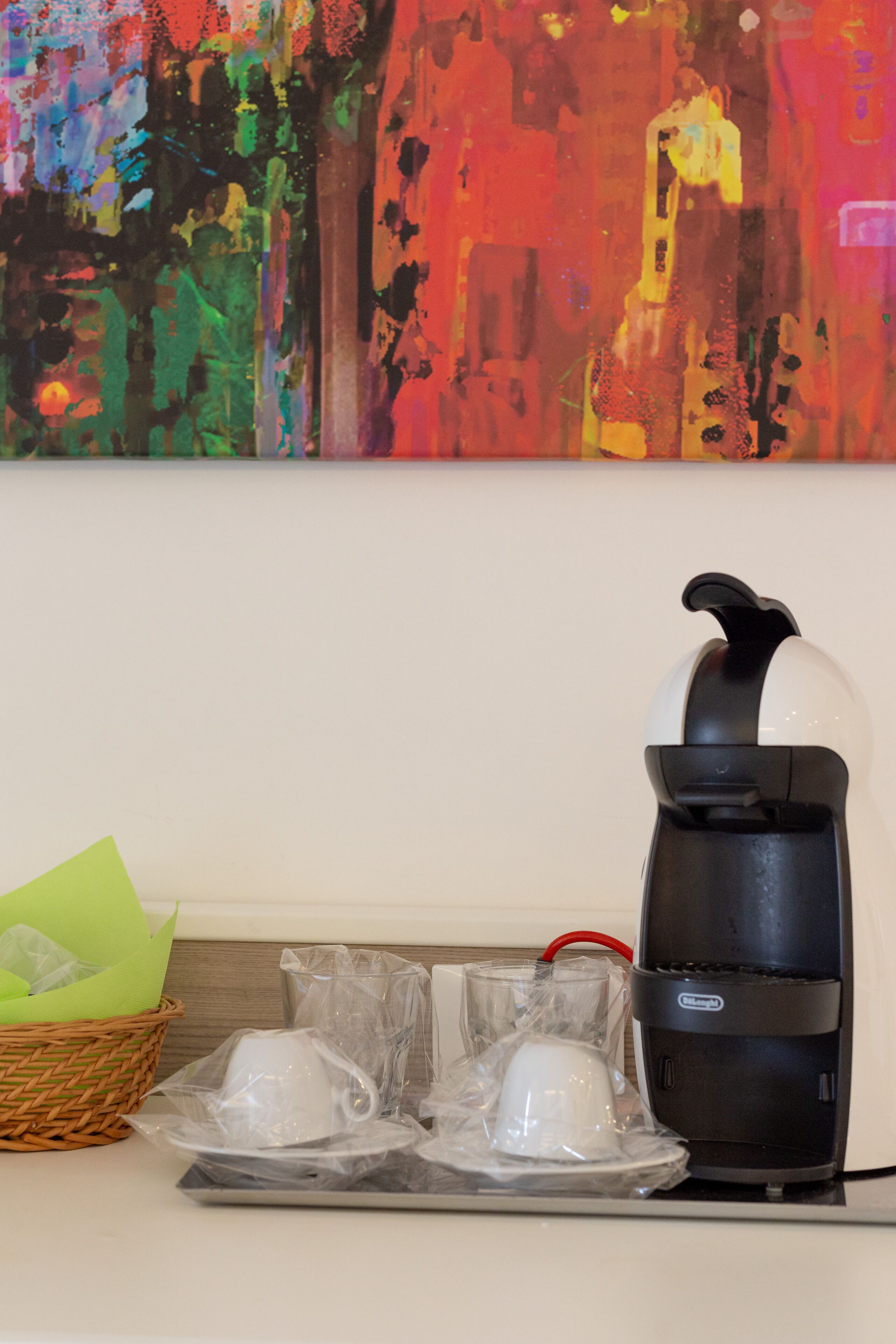 A coffee maker with a basket and cups on a table.