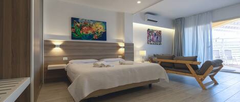 A modern bedroom with a large bed, bedside tables, a sofa, and artwork on the walls.