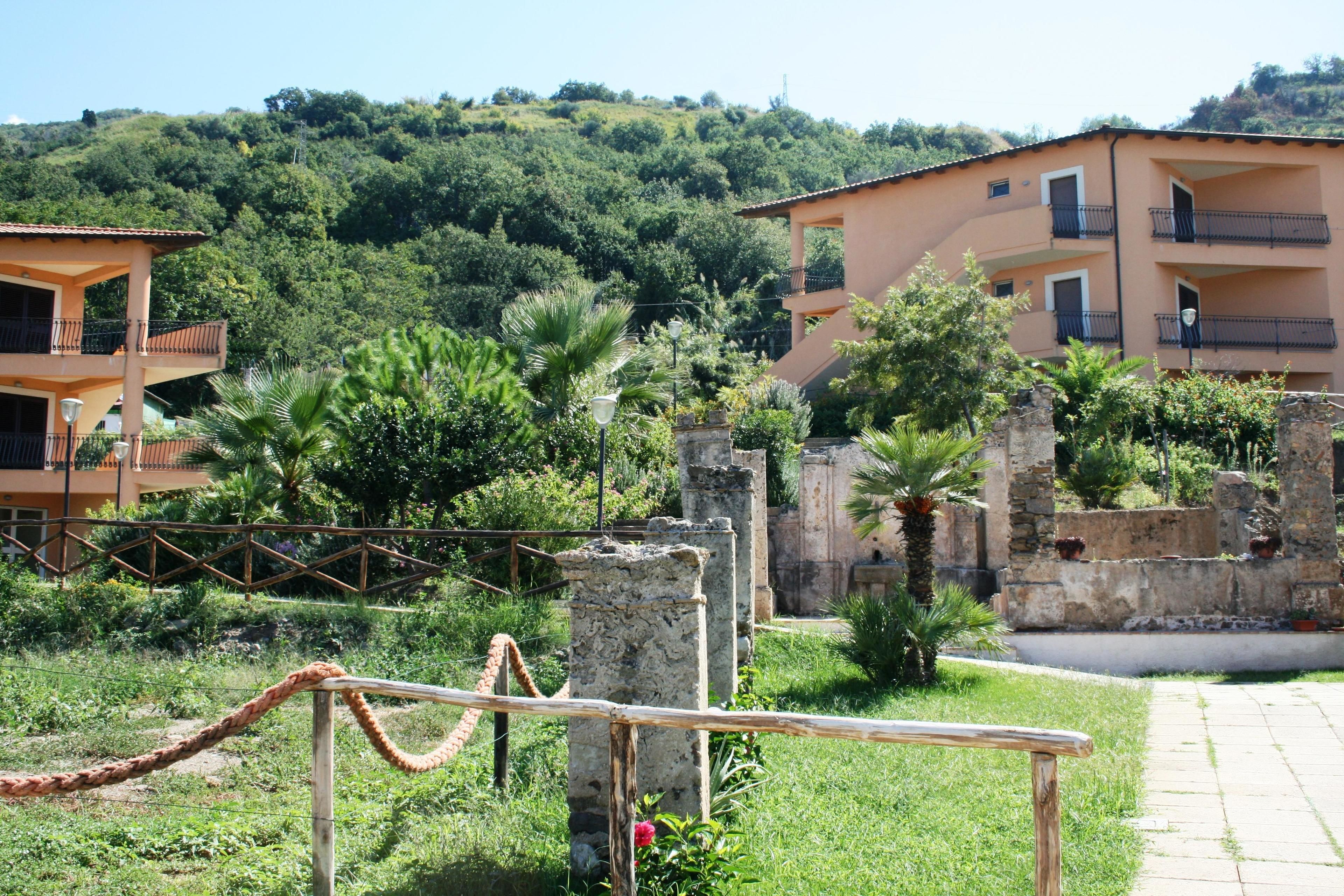 A historic site with ruins and a modern building with balconies.