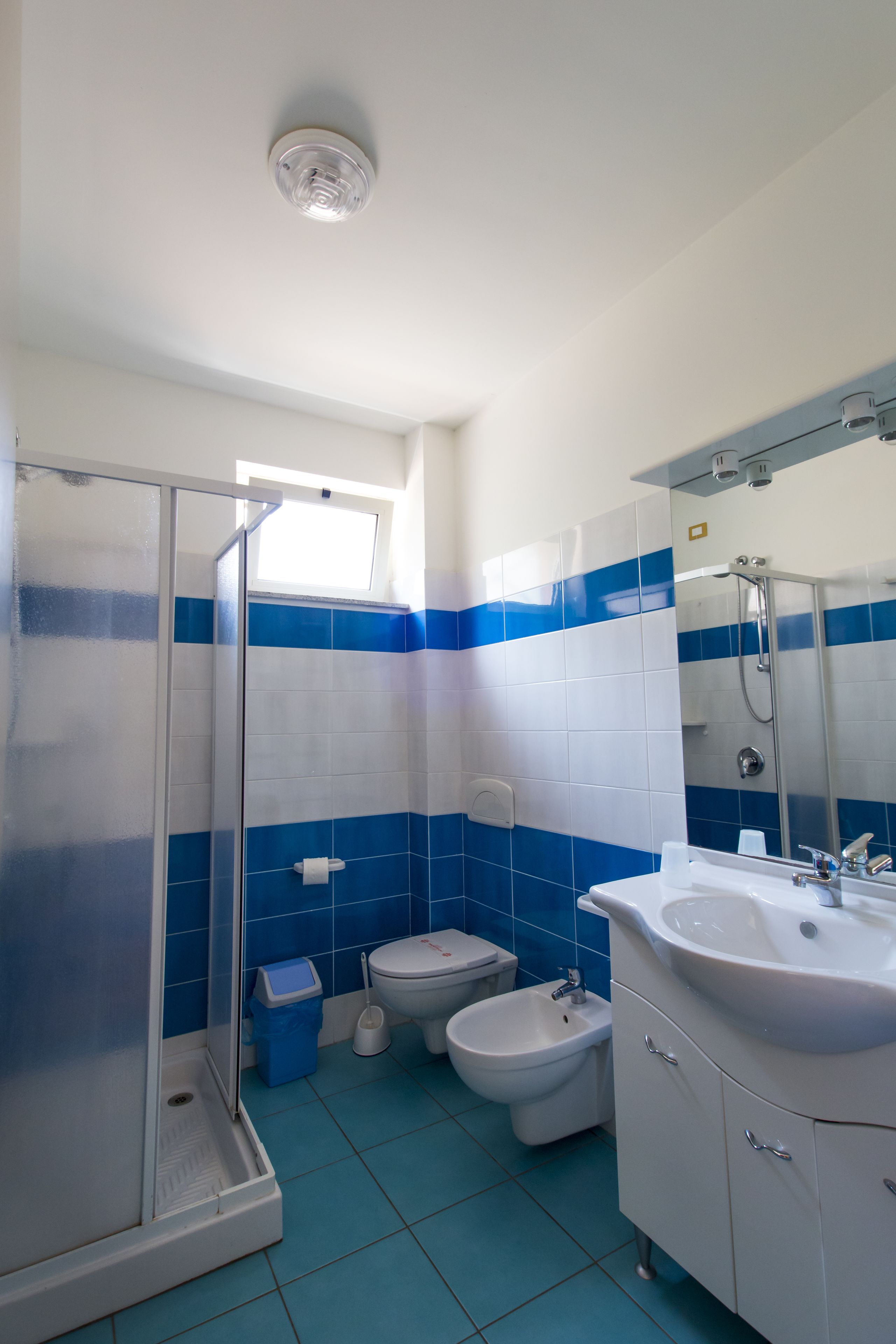 A bathroom with a shower, bidet, and sink.