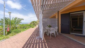 An outdoor patio with a white pergola, brick flooring, and a table with chairs.