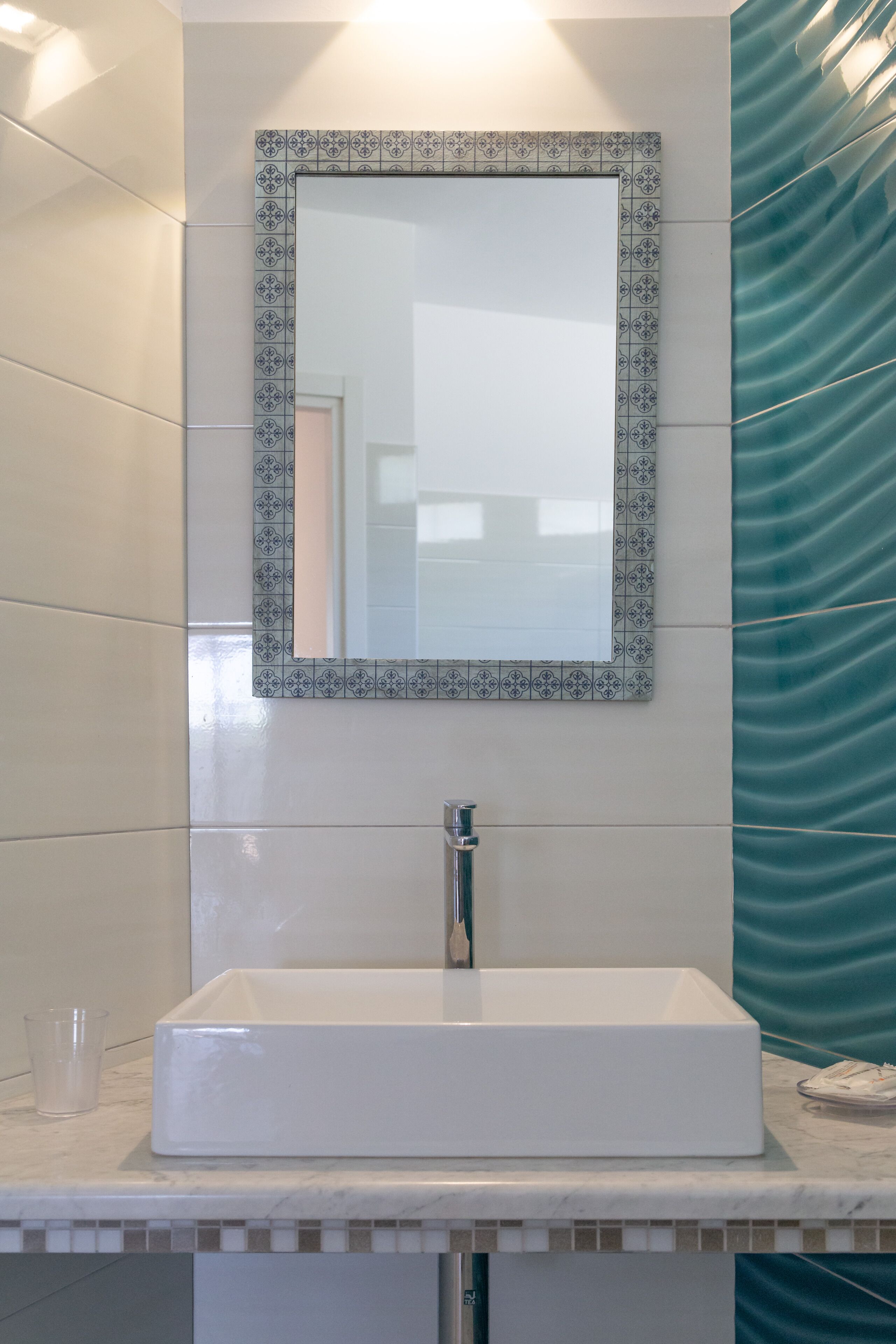 A bathroom with a white sink, a mirror with a decorative frame, and a teal-colored shower curtain.