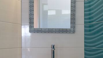 Un baño con lavamanos blanco, un espejo con marco decorativo y cortina de ducha color turquesa.