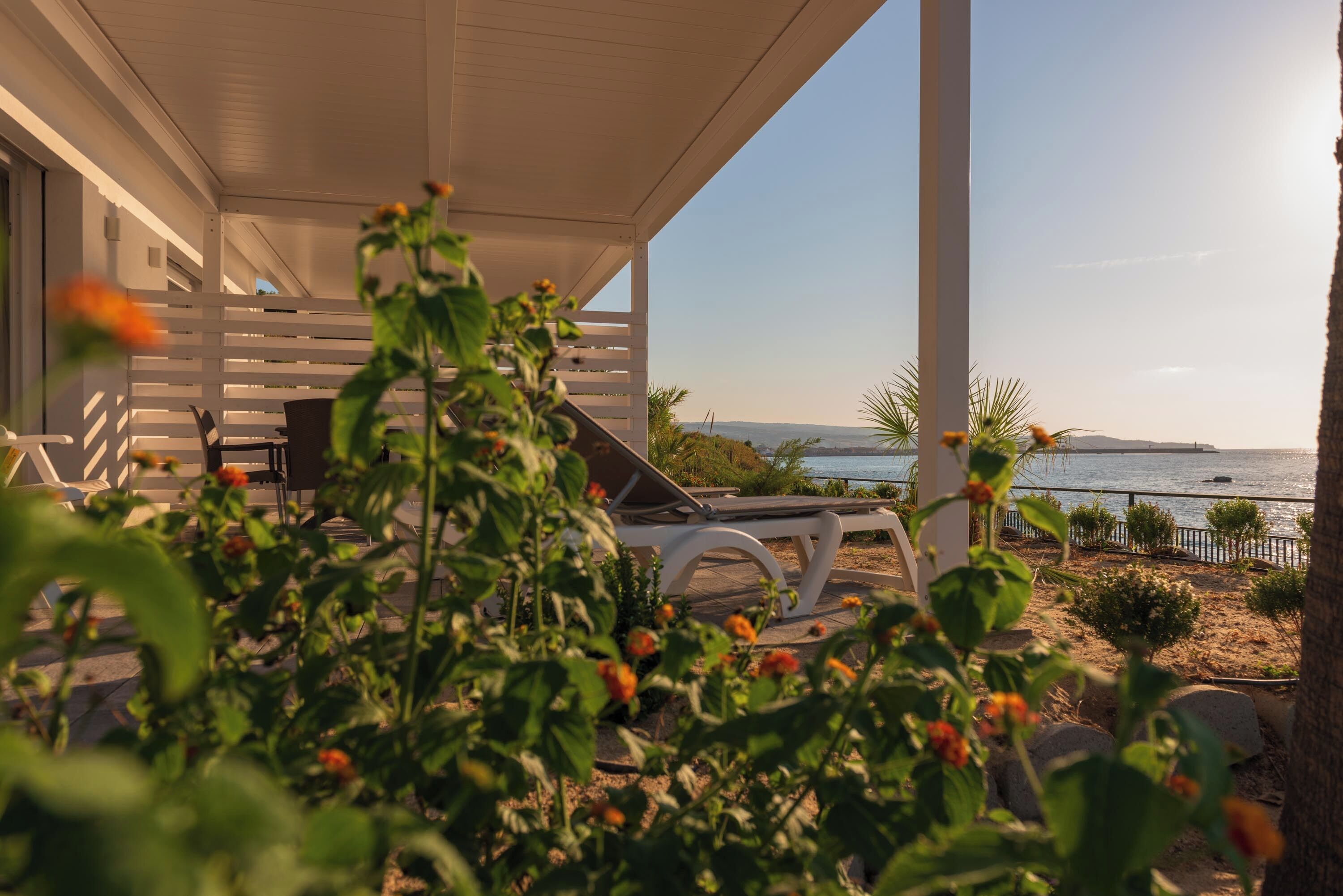 Un espacio al aire libre cubierto con piscina, sillones de descanso y vistas al mar.