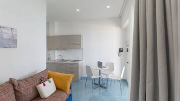 Un espace de vie compact comprenant un canapé, une petite table à manger et une kitchenette.