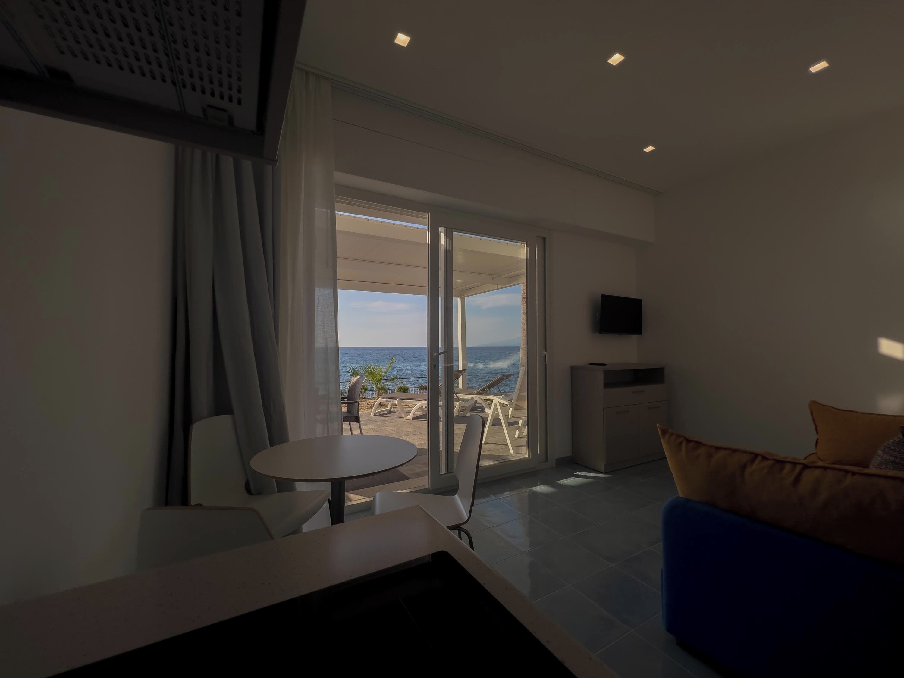 A modern living room with a balcony, a dining area, and a TV mounted on the wall.