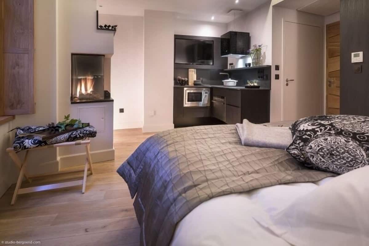 Une chambre moderne avec un grand lit, un petit coin cuisine et un banc en bois.