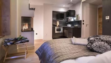 Un dormitorio moderno con una cama grande, una kitchenette pequeña y un banco de madera.
