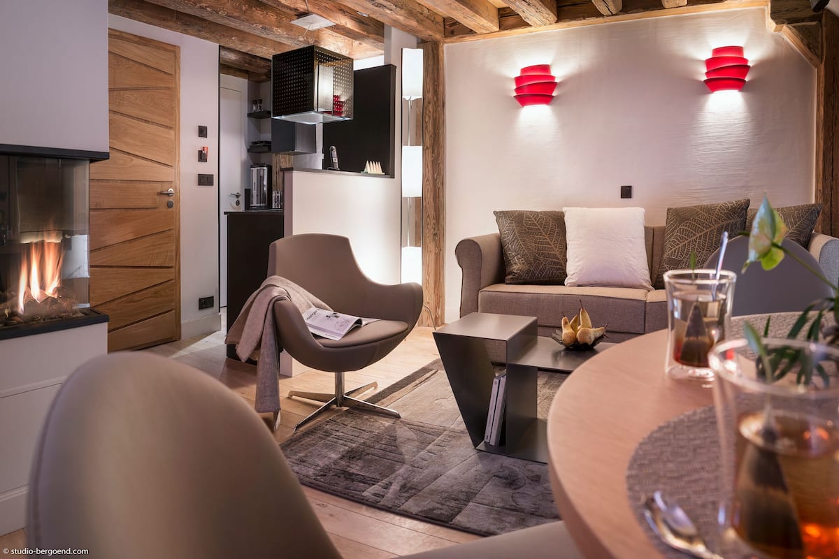 Un salon moderne avec une cheminée, un canapé, une table basse et un coin repas.