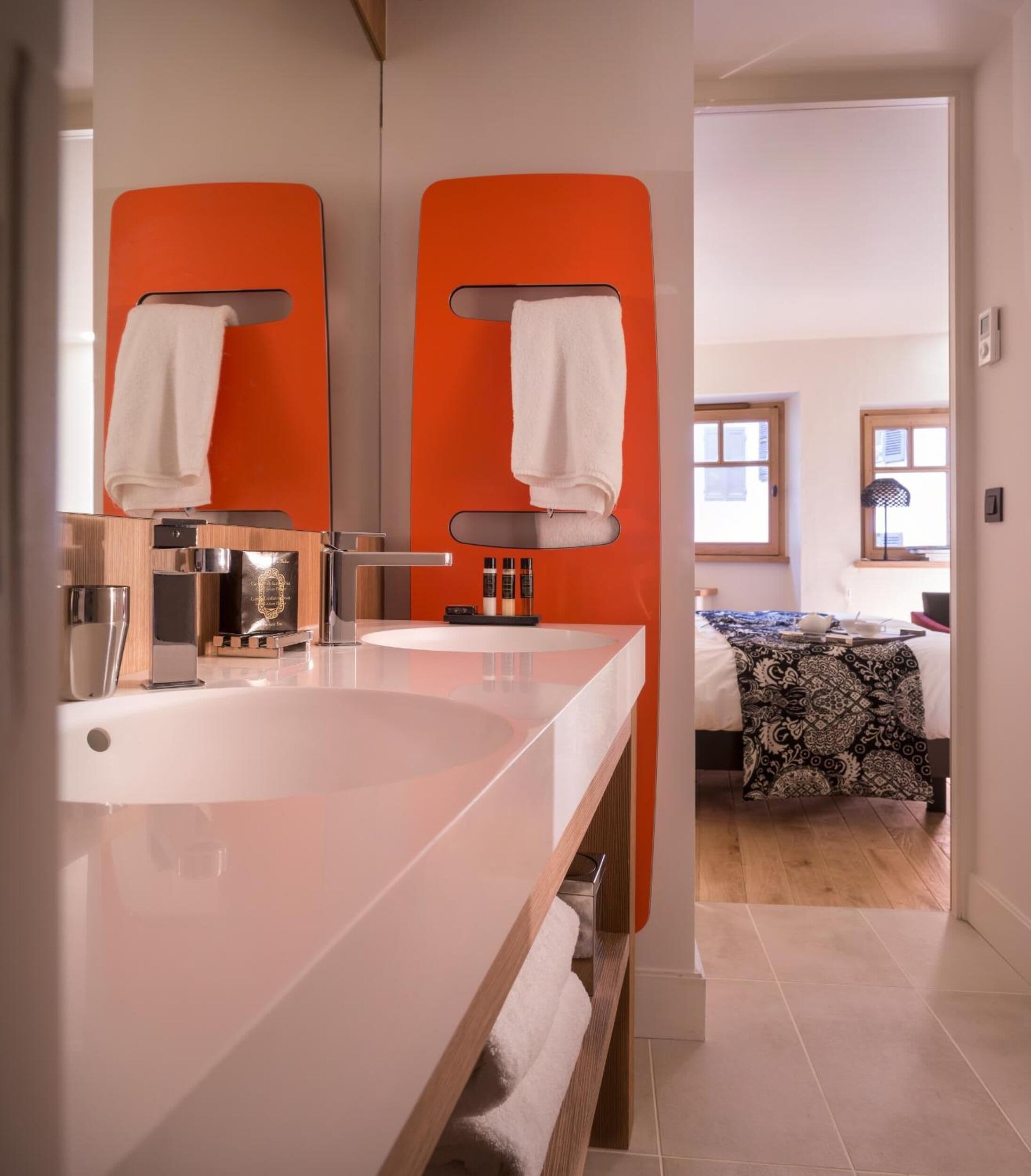 Un baño moderno con dos lavamanos, un espejo grande y un perchero para toallas.