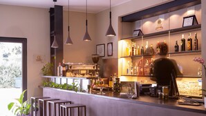 Una zona de bar con mostrador, taburetes y estanterías llenas de botellas.