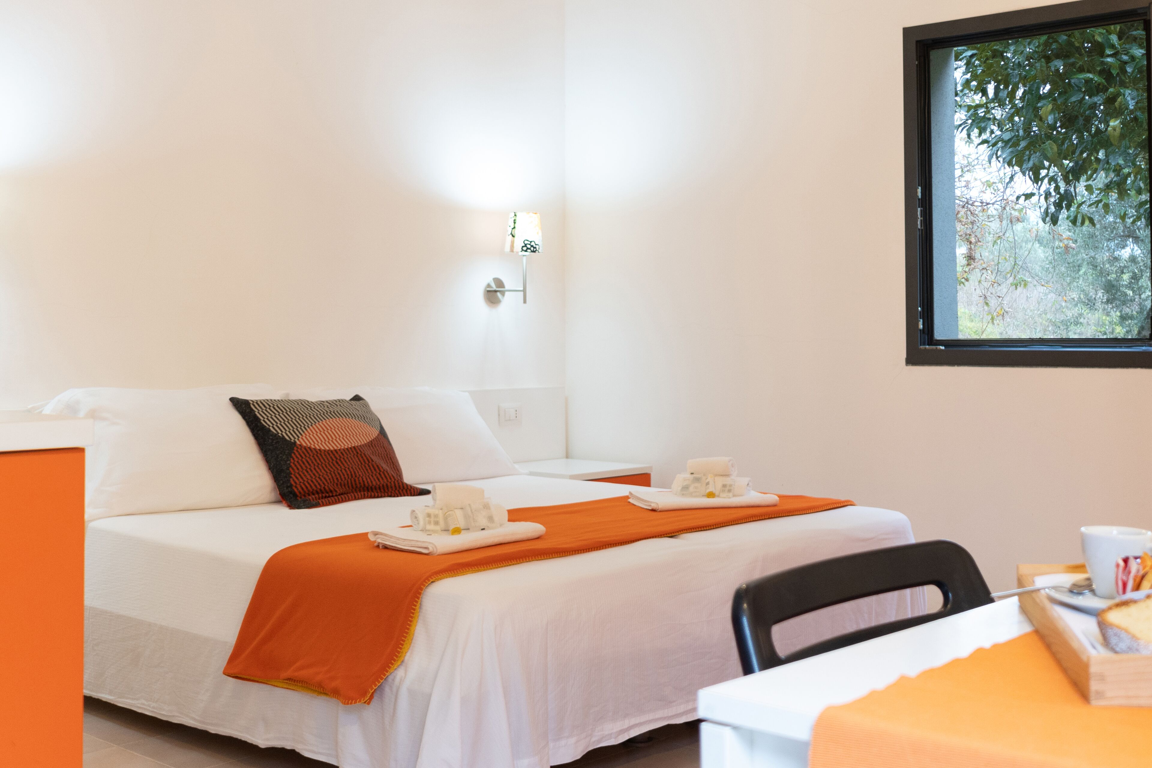 Una camera d'albergo con un letto, un tavolo e una finestra vista alberi.