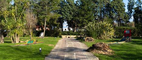 Ein gepflasterter Weg in einem Park mit Bäumen und einem Spielplatz.