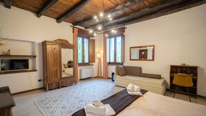 Una habitación de hotel con techo de madera, una cama grande, un sofá, un escritorio y un espejo.