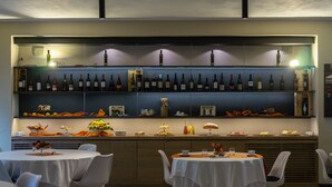Un restaurante con barra de vinos, mesas con manteles blancos y sillas.