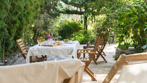 Un área de comedor al aire libre con una mesa para dos, rodeada de sillas de madera.