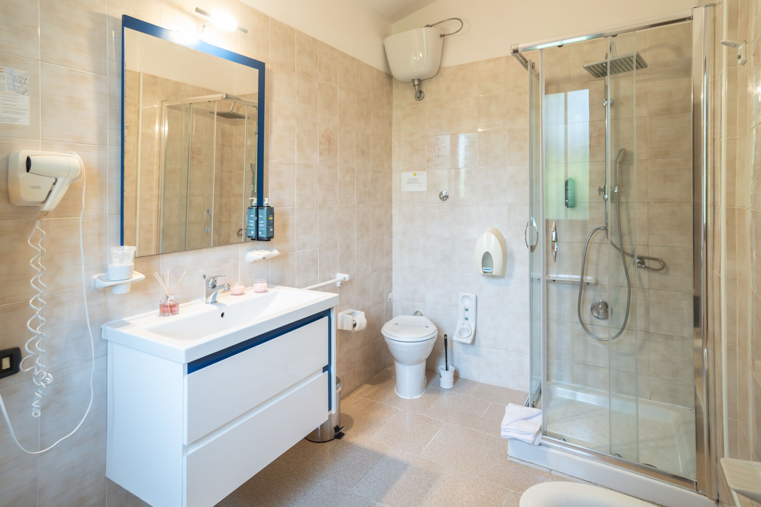 Un bany modern amb dutxa envidriada, un lavabo blanc amb mirall i un vàter.