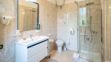 Un bany modern amb dutxa envidriada, un lavabo blanc amb mirall i un vàter.
