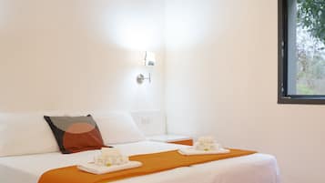 A hotel room with a bed, a nightstand, a lamp, and a window.