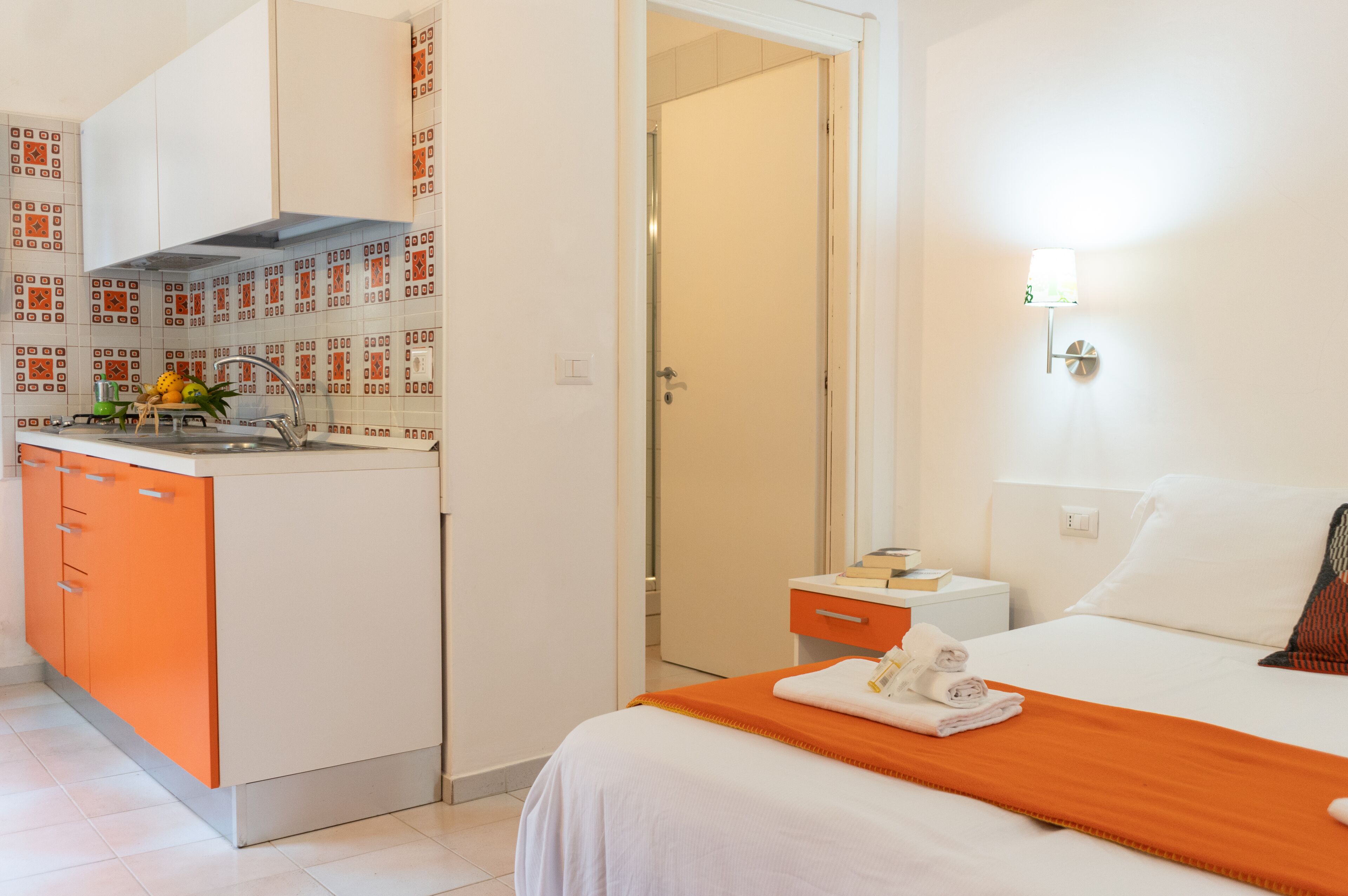 A hotel room with a bed, a bathroom, and a kitchenette.