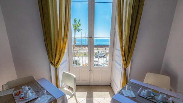 A balcony with two tables, each set with white tablecloths, plates, and cups. - Bed & Breakfast Ipnos (Catania)