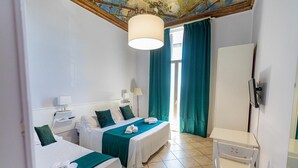 A hotel room with two beds, a desk, a TV, and a large window with curtains. - Bed & Breakfast Ipnos (Catania)