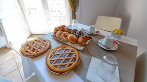 A breakfast table with pies, croissants, and pastries, a coffee cup, and a glass of water. - Bed & Breakfast Ipnos (Catania)