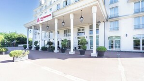 Ein Hotel mit Eingangsbereich, einer überdachten Laube, Säulen und Topfpflanzen.